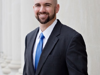 Man in suit smiling near white columns.